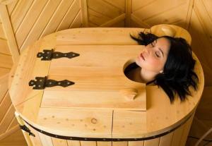 a woman is sitting in a wooden round table at Villa Rupcovoto in Smolyan