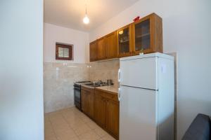 a kitchen with a white refrigerator and wooden cabinets at Apartments Gordana in Mimice