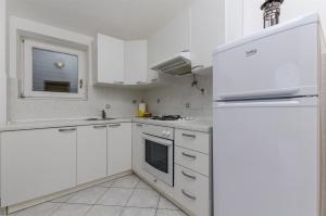 a white kitchen with white cabinets and a refrigerator at Apartments Ivan in Sevid