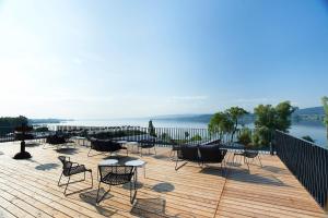 eine Terrasse mit Stühlen und Tischen und Blick auf das Wasser in der Unterkunft Hotel Bora HotSpaResort in Radolfzell am Bodensee