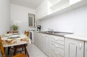 a white kitchen with a sink and a table at Apartments Anka in Duće