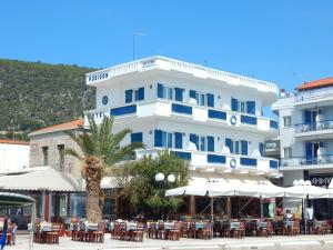 a white building with tables and chairs in front of it at Poseidon in Ancient Epidauros