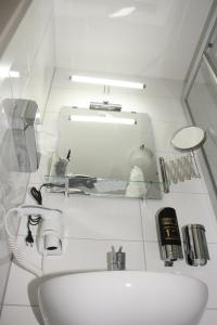 a white bathroom with a sink and a mirror at Hotel Vesa in Sindelfingen +24 photos
