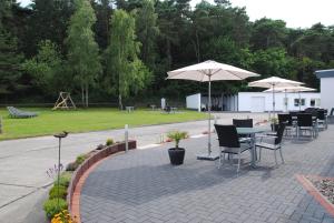 eine Terrasse mit Tischen, Stühlen und Sonnenschirmen in einem Park in der Unterkunft Appartementanlage-Ferienwohnungen Weiße Möwe in Sassnitz