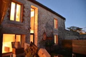 una casa de ladrillo con ventanas delante en Les Maillettes en Les Épesses