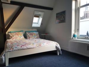 a bedroom with a bed and two windows at Large Historical Apartment & Canal Terrace in Utrecht
