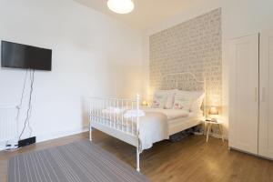 ein weißes Schlafzimmer mit einem Kinderbett und einem TV in der Unterkunft Stylish & Cosy Apartment in Berlin, WiFi in Berlin + 5 Fotos