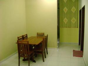 a dining room with a wooden table and chairs at Homestay Amsyarah in Seri Iskandar