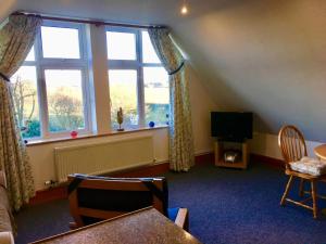 a living room with a large window and a television at Little Glebe in Sherborne