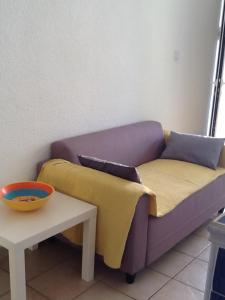 un sofá púrpura con 2 mantas y una mesa en Locations Meublées Plage des Pins en Argelès-sur-Mer