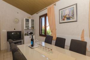 Un comedor con mesa y sillas y un televisor. en Apartments Denis, en Supetar