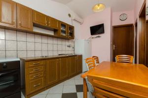 a kitchen with wooden cabinets and a table with chairs at House Barbarina in Rogač