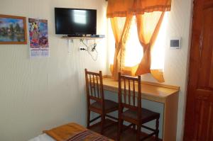 a bedroom with a desk with two chairs and a television at Acropolis Hostal in La Serena