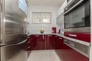 a kitchen with red cabinets and a stainless steel refrigerator at Apartments Mare in Postira