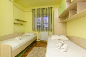 two beds in a room with a window at Apartments Mare in Postira