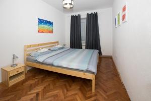een slaapkamer met een bed en een houten vloer bij Downtown 3 Bedroom Apartment in Sarajevo