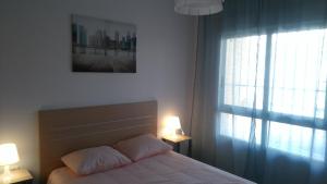 トレビエハにあるApartamento a 150m de la playa en Torreviejaのベッドルーム1室(ランプ2つ、窓付)
