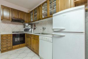 a kitchen with a white refrigerator and wooden cabinets at Apartments Ita in Postira