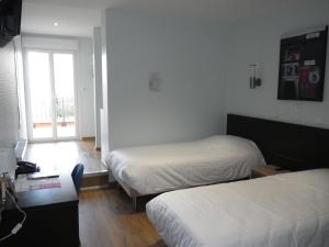 a hotel room with two beds and a window at Hôtel François 1er in Saint-Dizier