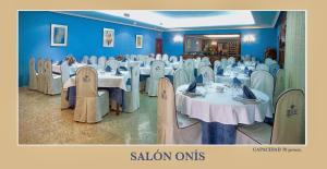 a dining room with white tables and chairs and blue walls at Hotel Royal in Llanera