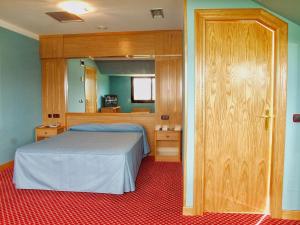 a bedroom with a bed and a wooden door at Hotel Royal in Llanera