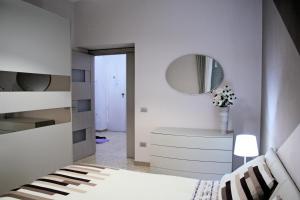 a white bedroom with a bed and a mirror at La Casa di Giulia in Caserta
