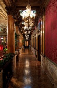 a long hallway in a building with a chandelier at Grand Hotel Plaza in Rome