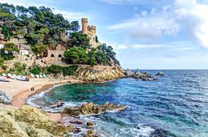 a beach with a castle on top of a mountain at htop Amatista #htopBliss in Lloret de Mar