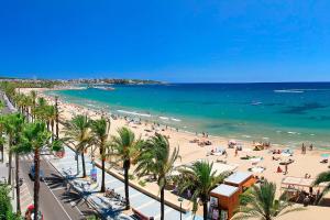 a beach with people and palm trees and the ocean at htop Molinos Park #htopEnjoy in Salou
