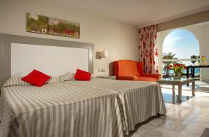a hotel room with a bed and an orange chair at Ona Marinas de Nerja Spa Resort in Nerja