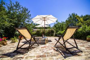 two chairs and a table with an umbrella at Country House Case Catalano in Abbateggio