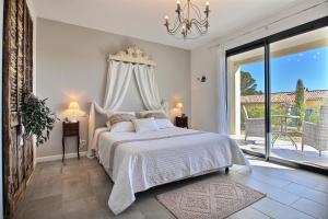 a bedroom with a white bed and a large window at La Villa Aux Oliviers in Flayosc