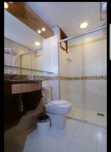 a bathroom with a toilet and a glass shower at Manacá Apartamentos , Kariri Beach , Cumbuco in Cumbuco