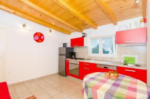 a kitchen with red cabinets and a table at House Mislav in Velike Kuknjare
