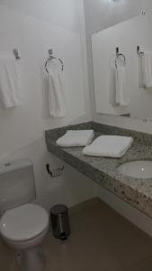 a bathroom with a toilet and a sink and a mirror at Hotel Pit Stop Oliveira-MG in Oliveira