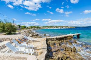a group of white chairs sitting on a beach at House Mislav II in Velike Kuknjare +12 photos
