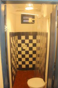 a bathroom with a checkered shower with a toilet at Adios Amigos Hostel in Arraial d'Ajuda