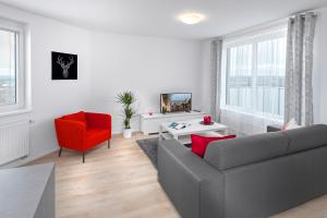 salon z kanapą i czerwonym krzesłem w obiekcie CityWest Apartments w Pradze