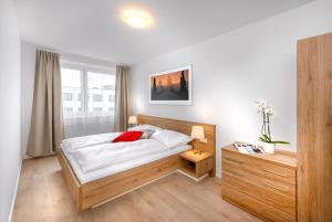 una camera da letto con un letto con lenzuola bianche e cuscini rossi di CityWest Apartments a Praga