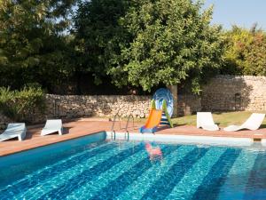a swimming pool with chairs and an infront of a pool at La Casetta Sicilian Cottage in Case Rosolia