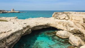 an arch in a rock formation in the ocean at casa azzurra in San Foca