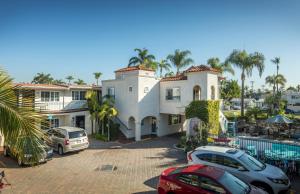 une grande maison blanche avec des voitures garées devant elle dans l'établissement Crown City Inn Coronado, à San Diego