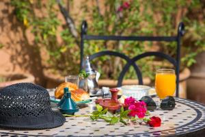 a table with a black hat and some orange juice at Riad Jnane Mogador in Marrakesh