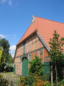un antiguo edificio de ladrillo con puertas verdes y techo rojo en Ferienwohnung am Elbdeich, en Bleckede