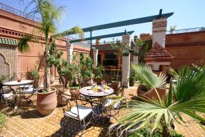 a patio with tables and chairs and palm trees at Riad Jnane Mogador in Marrakesh