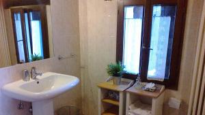 a bathroom with a white sink and two windows at La Piana Dei Castagni in Castel dʼAiano