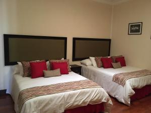 um quarto com 2 camas e almofadas vermelhas em Hotel Hacienda El Rodeo em Rodeo