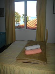 a bed with two towels on a wooden tray with a window at Residencia ANA in Santa Cruz