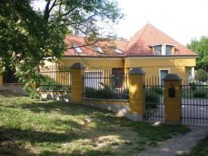 ein gelbes Haus mit einem schwarzen Zaun in der Unterkunft Anonim apartman in Villány
