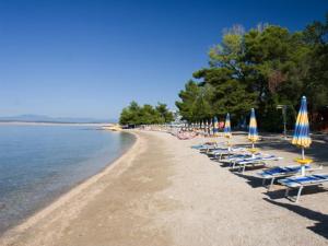 a beach with chairs and umbrellas and the water at Apartman Maria in Crikvenica